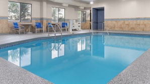 Ein Schwimmbecken mit klarem, blauem Wasser, umgeben von blauen Stühlen und einem Umkleideraum.