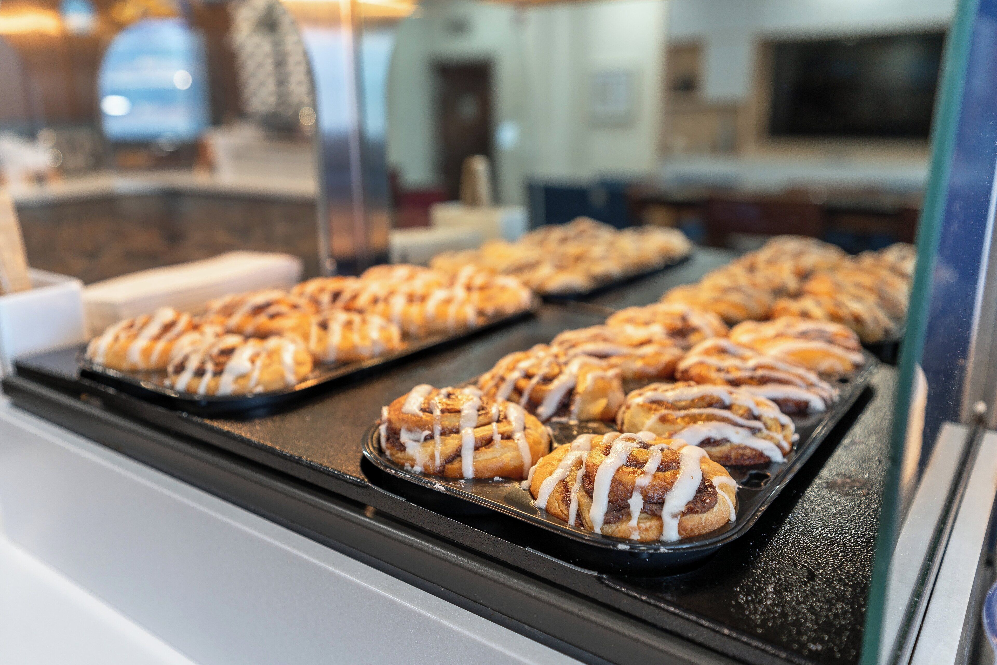 A display case with trays of cinnamon rolls.