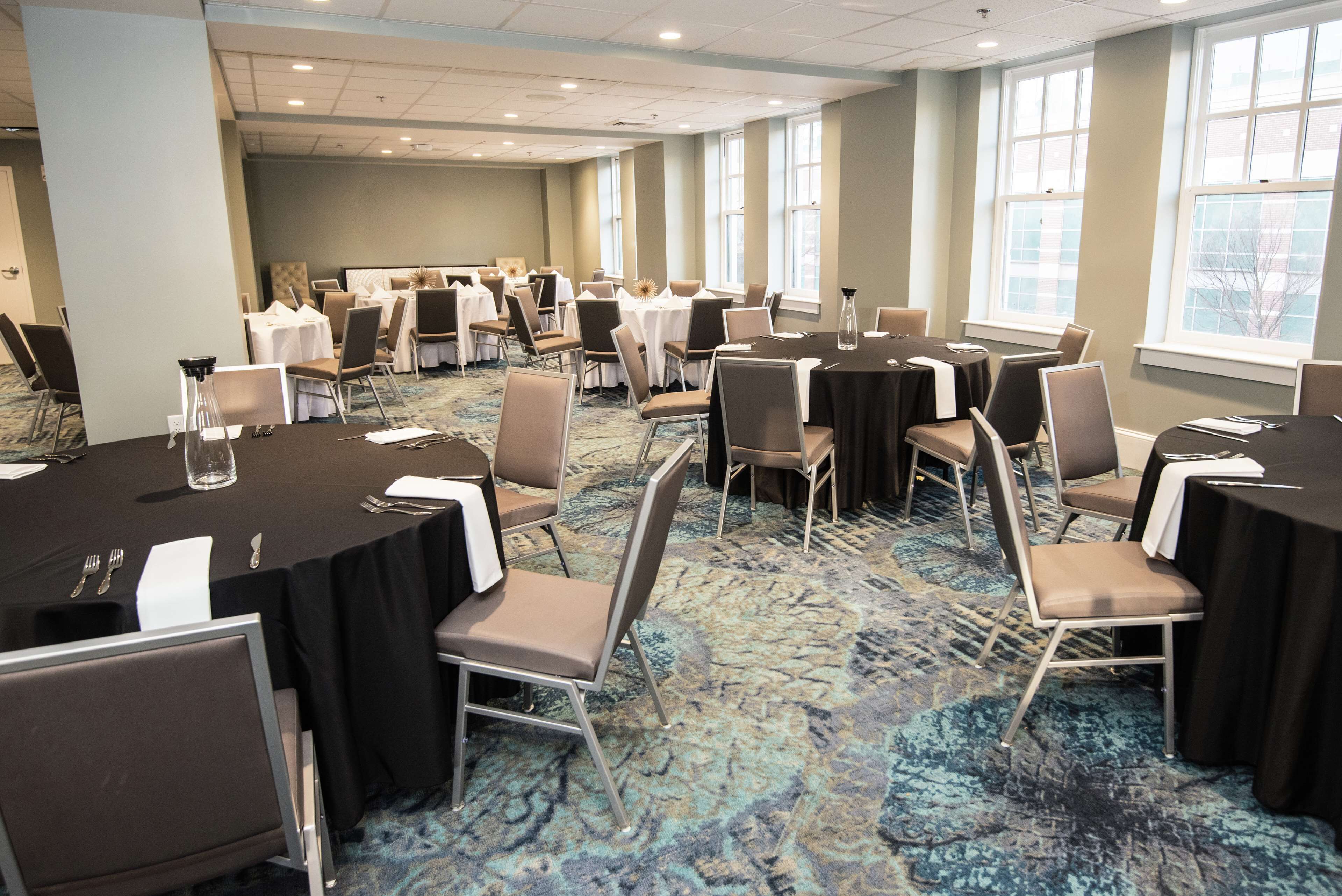 Une salle de conférence avec des tables rondes, des chaises et un sol recouvert de moquette.