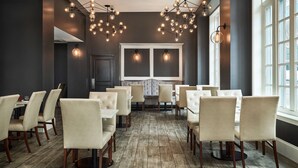 A dining area with multiple tables and chairs, a large window, and a modern chandelier. - Redmont Hotel Birmingham, Curio Collection by Hilton (Birmingham)