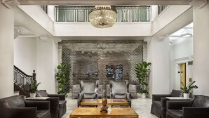 A spacious lobby with a high ceiling, a grand staircase, and a brick wall backdrop. - Redmont Hotel Birmingham, Curio Collection by Hilton (Birmingham)