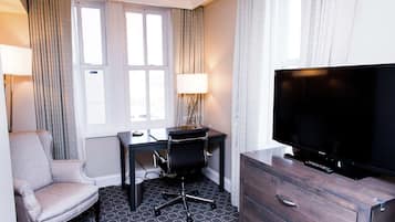 Habitación de hotel con escritorio, silla, televisor y cómoda.