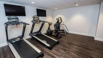 Ett gym med löpband, motionscyklar och en tv-skärm.