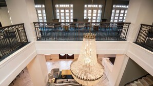 A spacious lobby with a grand chandelier, a staircase, and a seating area with sofas and tables. - Redmont Hotel Birmingham, Curio Collection by Hilton (Birmingham)