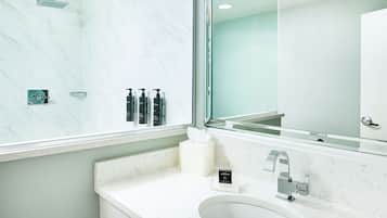 A modern bathroom with a large mirror, a sink, and a shower.