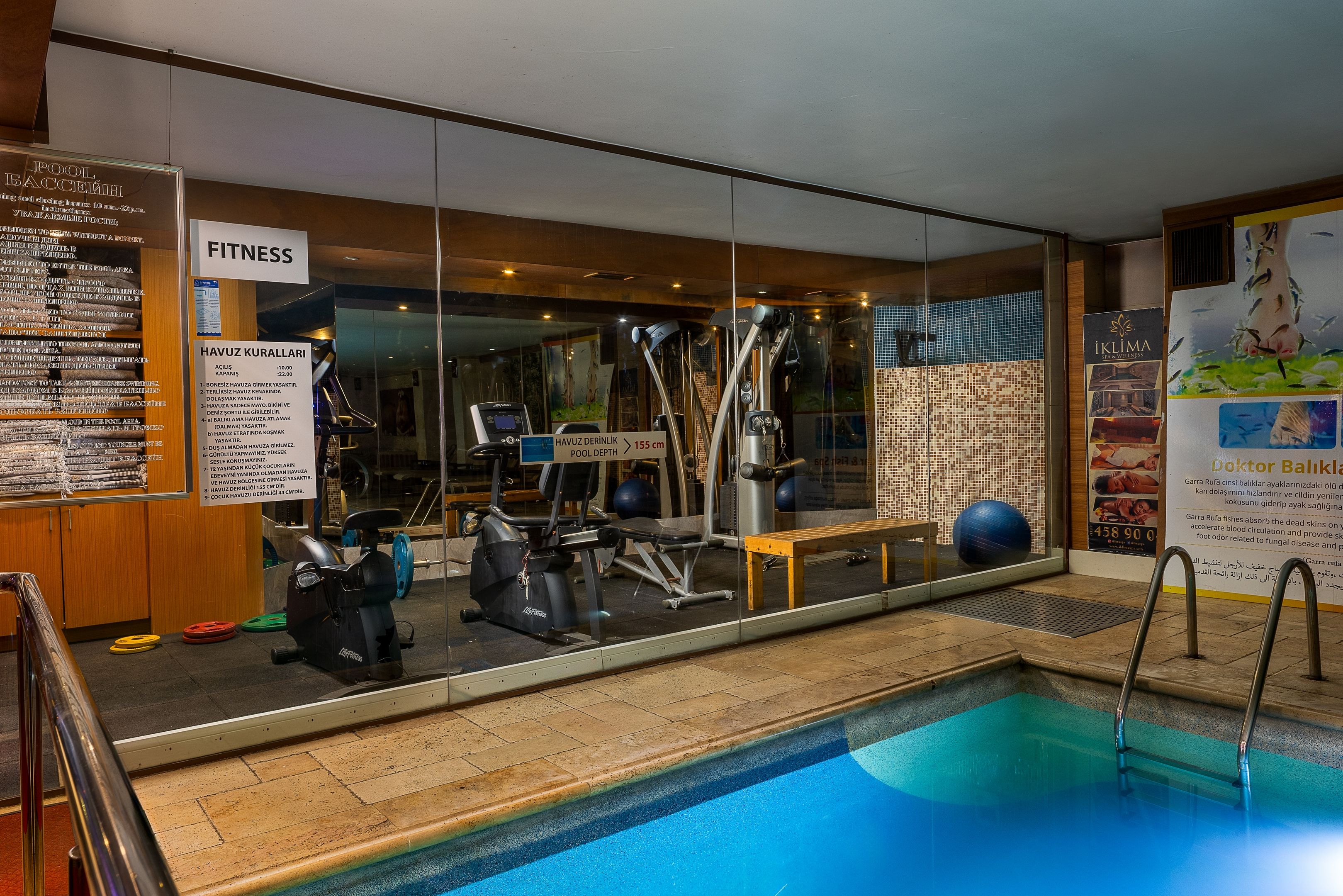 Un gimnasio con equipo de ejercicio, una piscina y un cartel que indica la profundidad del agua.