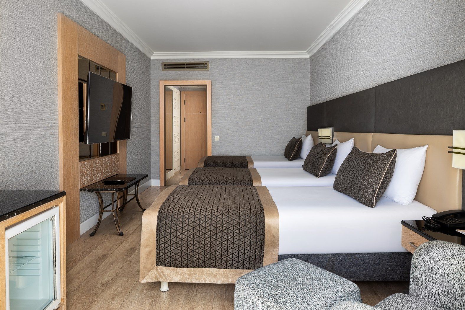 Quarto de hotel com cama, mesas de cabeceira, televisão e escrivaninha.