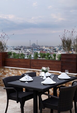 An outdoor dining area with a table set for two, overlooking a cityscape. - Darkhill Hotel (Istanbul)