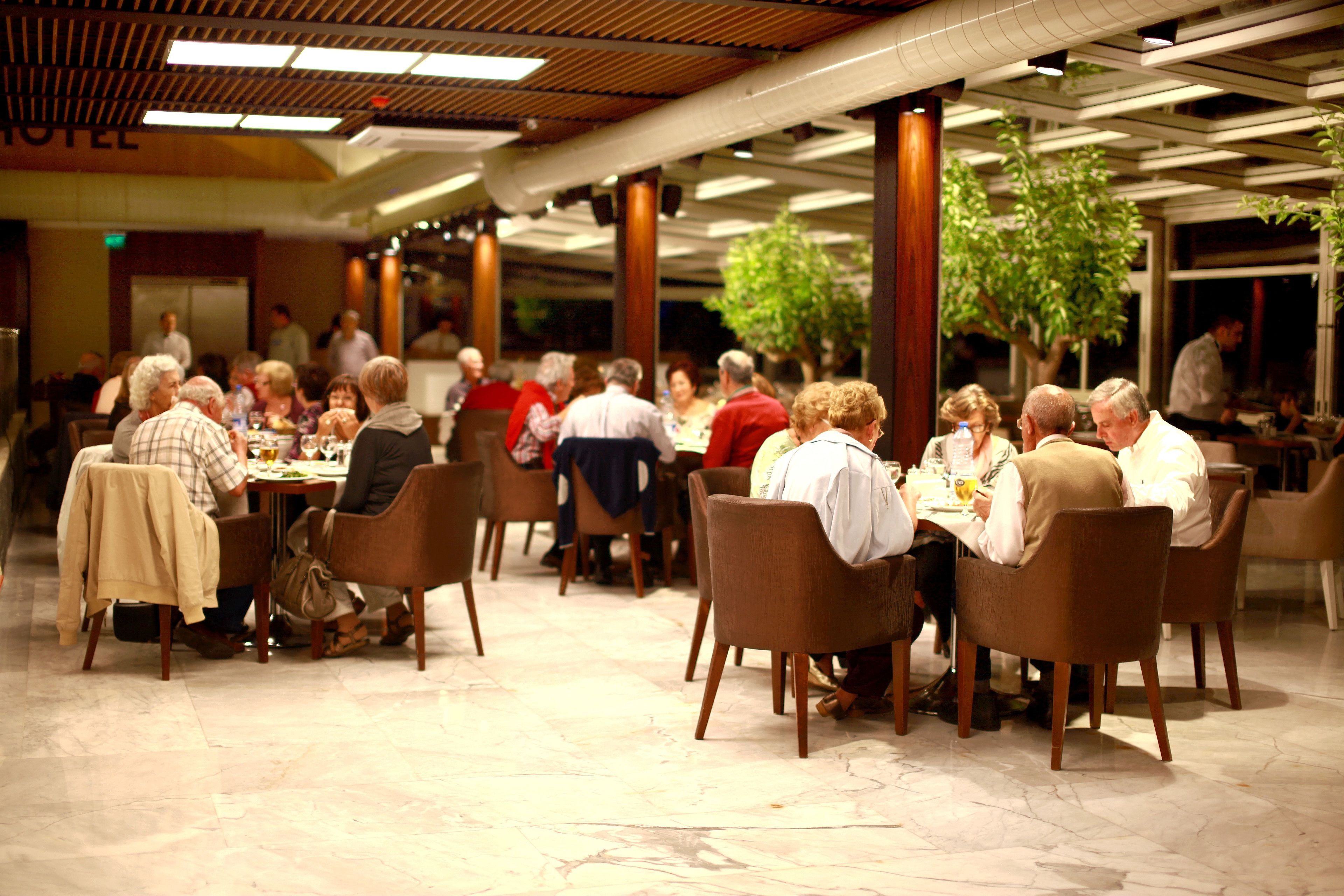 A spacious indoor dining area with marble flooring and wooden chairs.