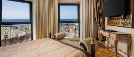 Une chambre spacieuse avec un grand lit, une télévision et un balcon offrant une vue sur la mer.