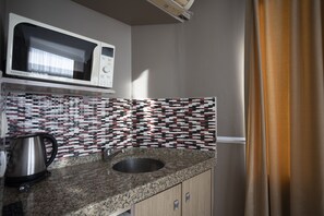 A kitchen with a microwave, sink, and patterned backsplash. - Tashkonak Hotel (Istanbul)
