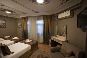 Habitació d'hotel amb dos llits, una taula de treball, una cadira, un mirall i una finestra amb cortines.