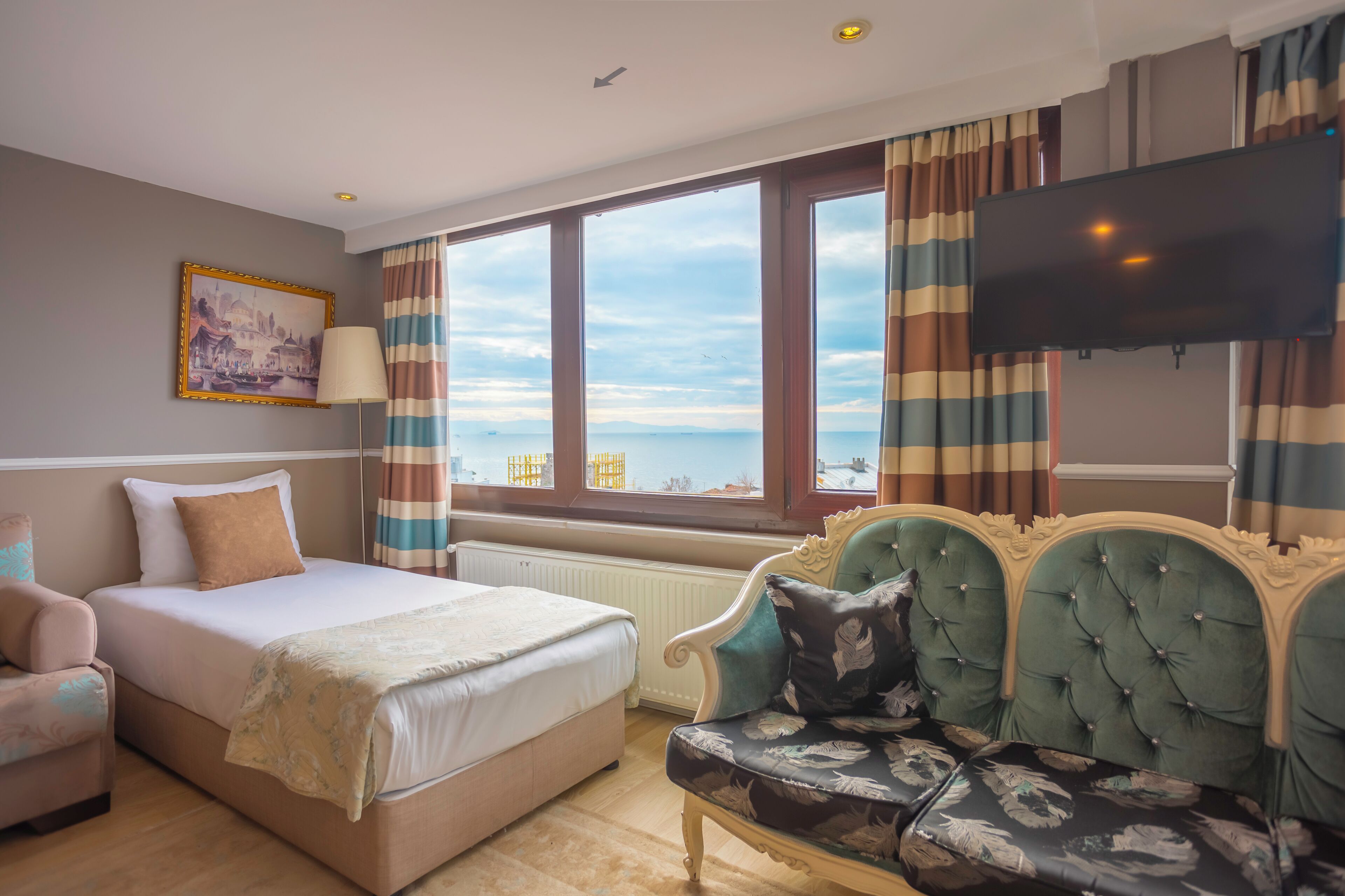 A hotel room with a bed, a sofa, a TV, and a window with a view.