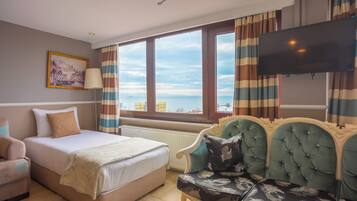 A hotel room with a bed, a sofa, a TV, and a window with a view.