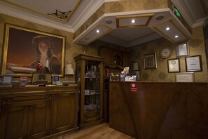 A reception area with a wooden counter, a framed portrait, and a clock on the wall. - Tashkonak Hotel (Istanbul)