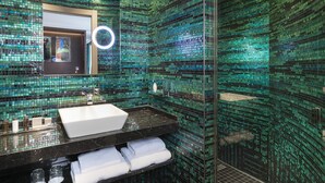 Un baño con un espejo grande, un lavabo blanco y una zona de ducha.