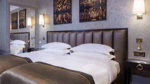 Habitación de hotel con una cama grande, dos lámparas de pared y dos cuadros enmarcados que representan escenas nocturnas.