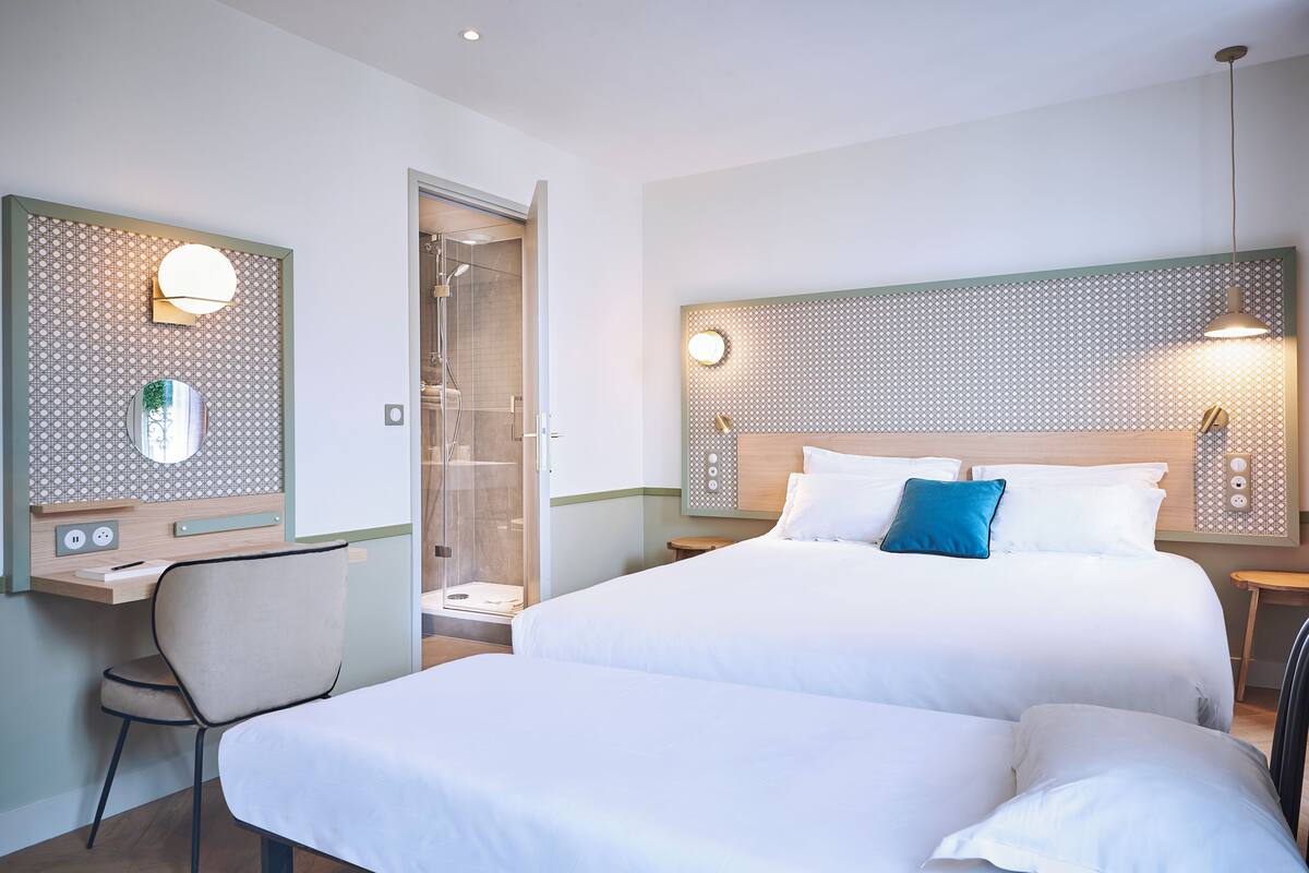 Een hotelkamer met een groot bed, een bureau met een stoel, een douche en een spiegel aan de muur.