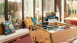 Une pièce lumineuse, avec une table de billard, des sièges confortables et de grandes fenêtres.