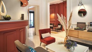 Un intérieur moderne avec un mur d’accent rouge, un coin salon avec un fauteuil et un canapé rouges, une table basse blanche et un coin cuisine avec une machine à café.