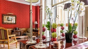 A room with a wooden desk, red patterned wallpaper, a framed picture on the wall, and a chair with striped upholstery. - Hotel Regence Paris (Paris)