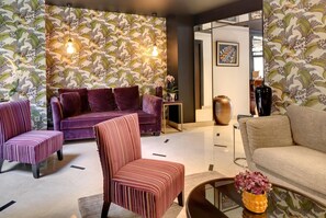 A modern living room with a patterned wallpaper, a purple sofa, a striped armchair, and a beige sofa. - Le Senat (Paris)