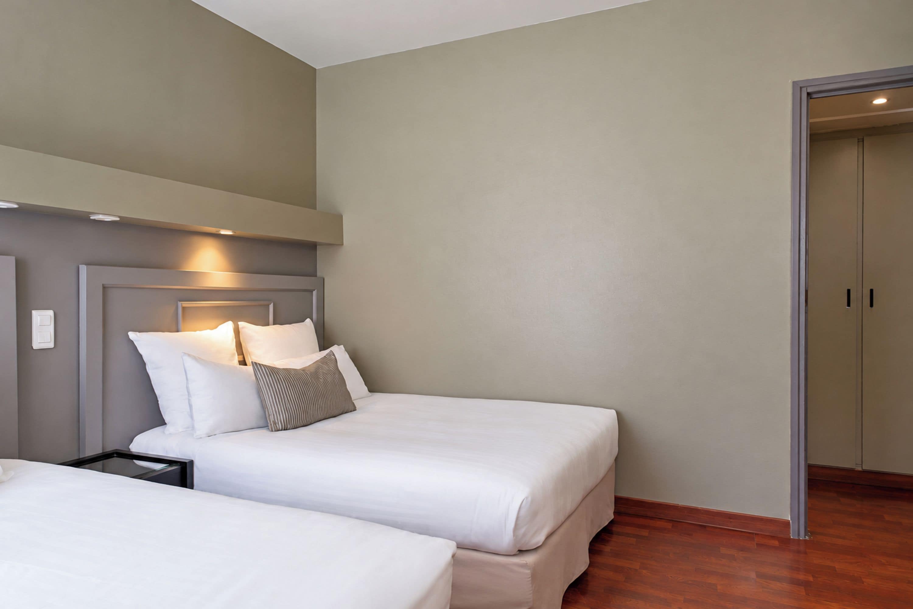 A hotel room with two beds, a nightstand, and a wardrobe.