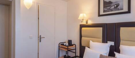A hotel room with a bed, bedside table, lamp, and a framed picture on the wall.