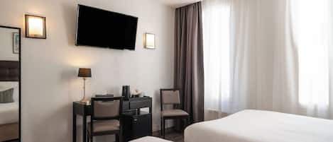 A hotel room with two beds, a desk with a chair, a television, and a window with curtains.