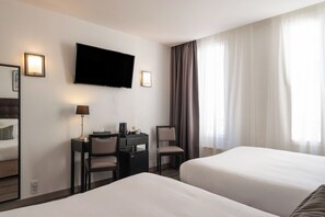 A hotel room with two beds, a desk with a chair, a television, and a window with curtains. - Hotel Cosmotel Marais République Paris (Paris)