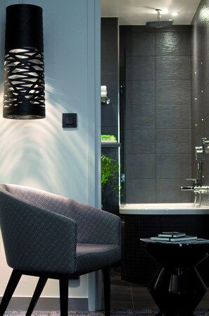 A modern bathroom with a bathtub, a towel rack, and a chair. - Le Grey Hotel (Paris)