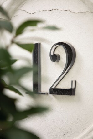 A house number sign with a decorative design on a textured wall. - Le Grey Hotel (Paris)