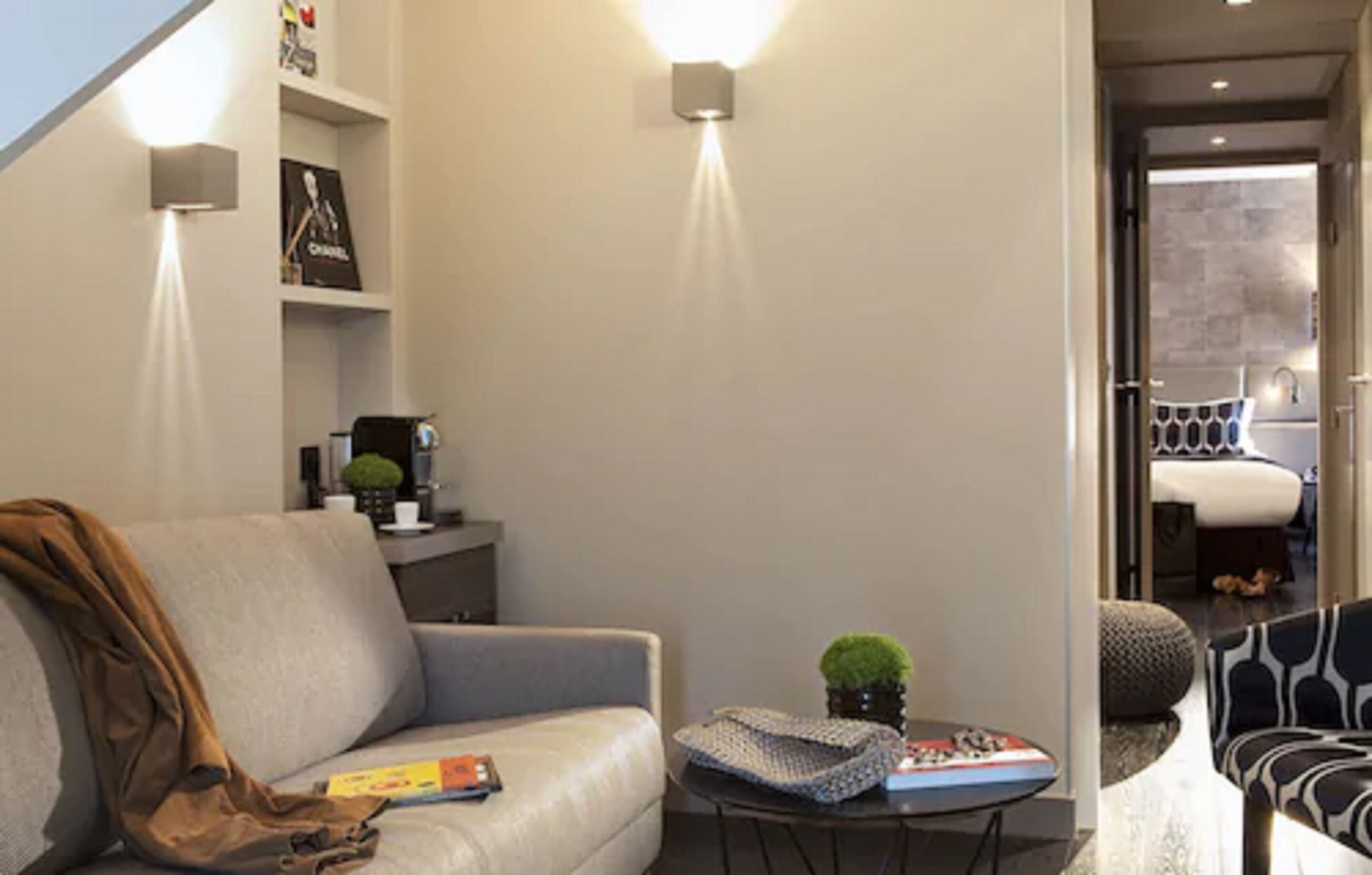 Una sala de estar moderna con un sofá gris, una mesita de centro con adornos y una estantería con marcos de fotos.