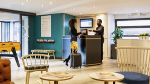 Un espace d’accueil comprenant un comptoir, des chaises, des tables et un écran de télévision.