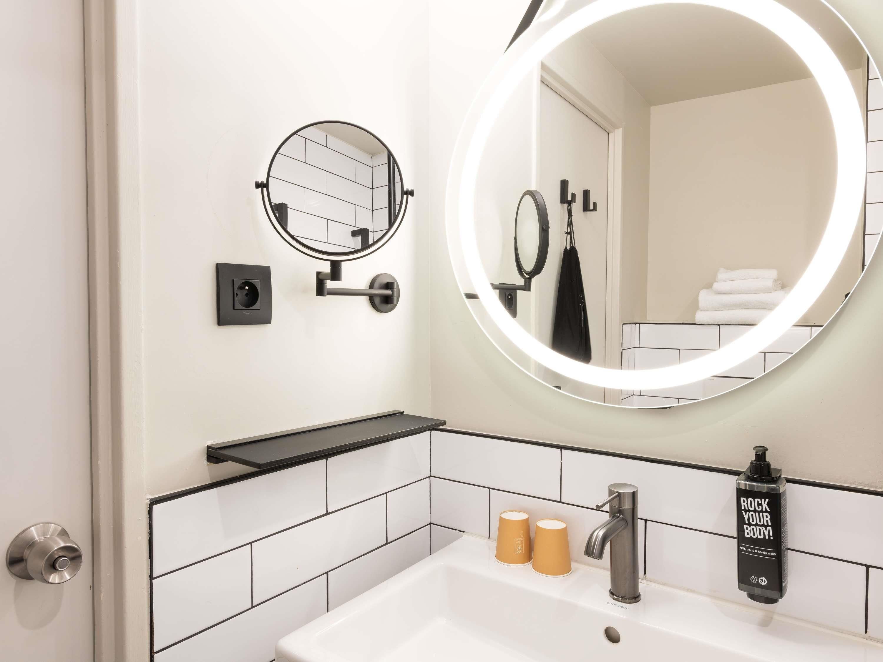 A bathroom with a round mirror, a sink, and a towel rack.