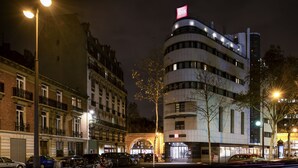 Un hôtel moderne à la façade incurvée, doté d'une enseigne lumineuse et d'une entrée imposante.