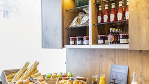 Un buffet de petit-déjeuner comprenant du pain, des viennoiseries, des fruits et des boissons.