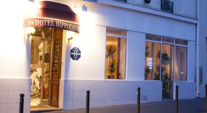 L’entrée d’un hôtel, avec une enseigne indiquant « HÔTEL HIPPODROMI » et une autre précisant qu’il s’agit d’un « HÔTEL TOURISTIQUE ».