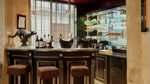 A bar area with a counter, stools, and shelves stocked with bottles and glasses. - Grand Hotel Francais (Paris)