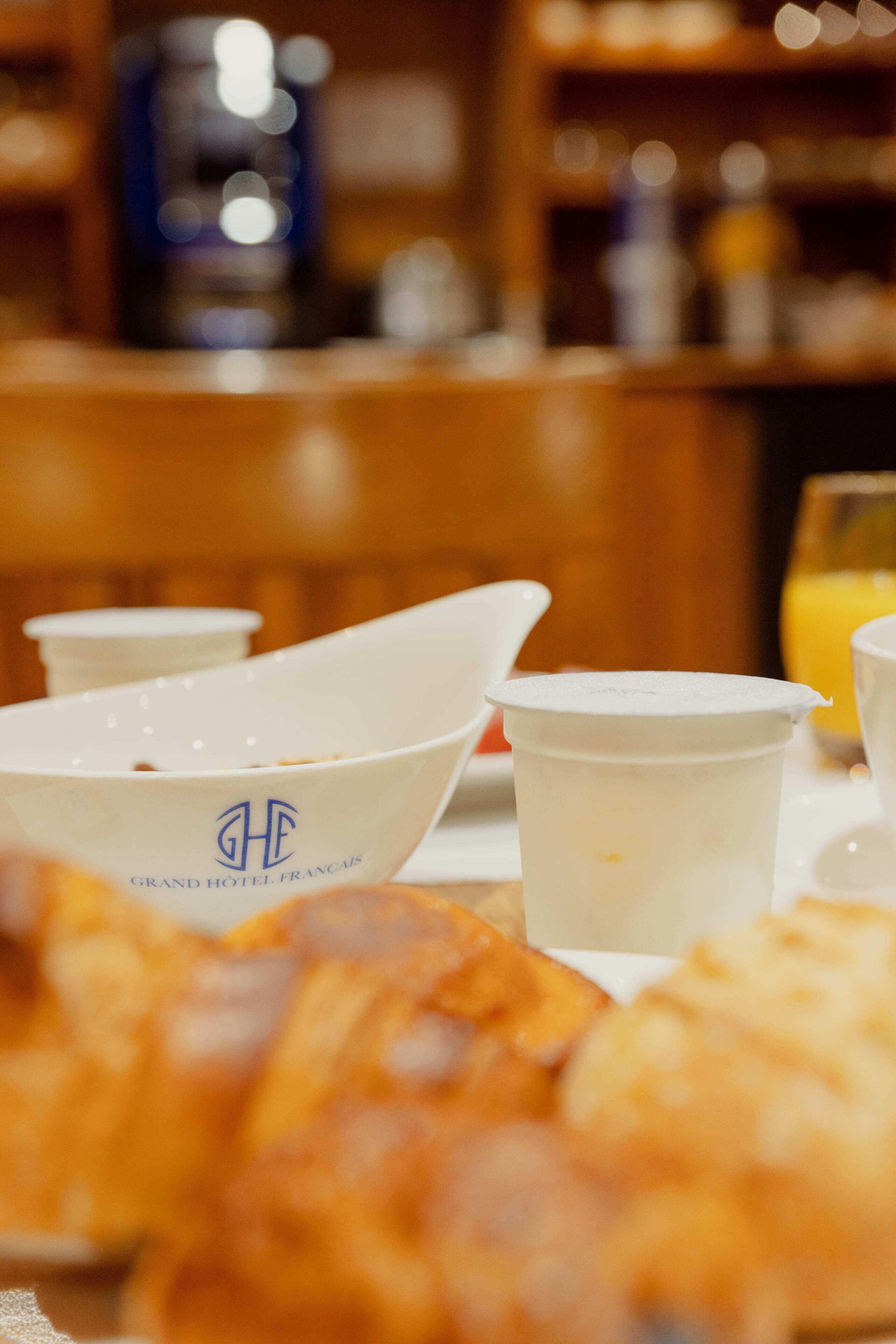 Una mesa con un croissant, una taza de café y un vaso de jugo para el desayuno.