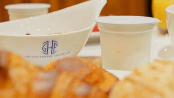 Una mesa con un croissant, una taza de café y un vaso de jugo para el desayuno.