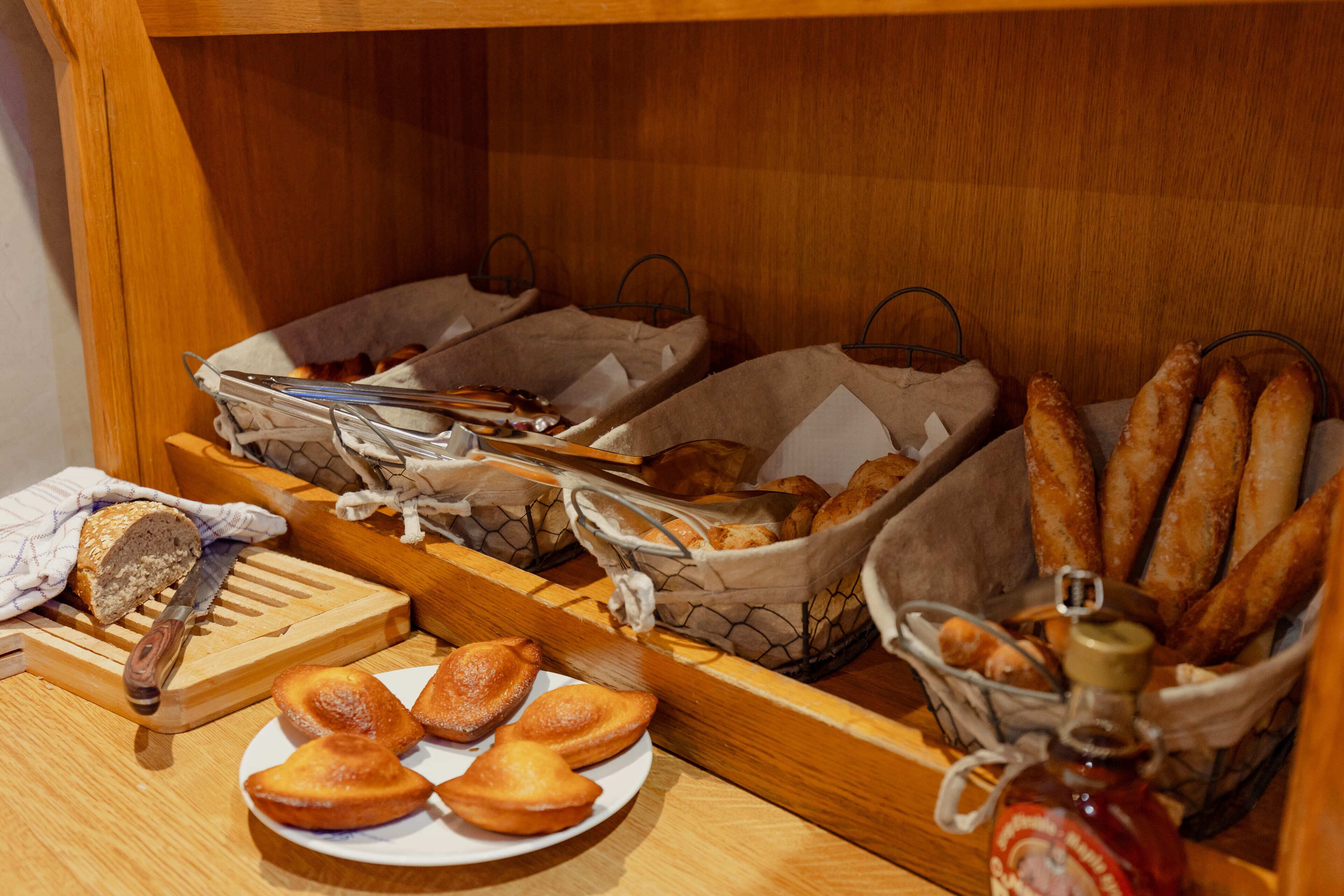 Un buffet de petit-déjeuner comprenant du pain, des viennoiseries et un pot de confiture.