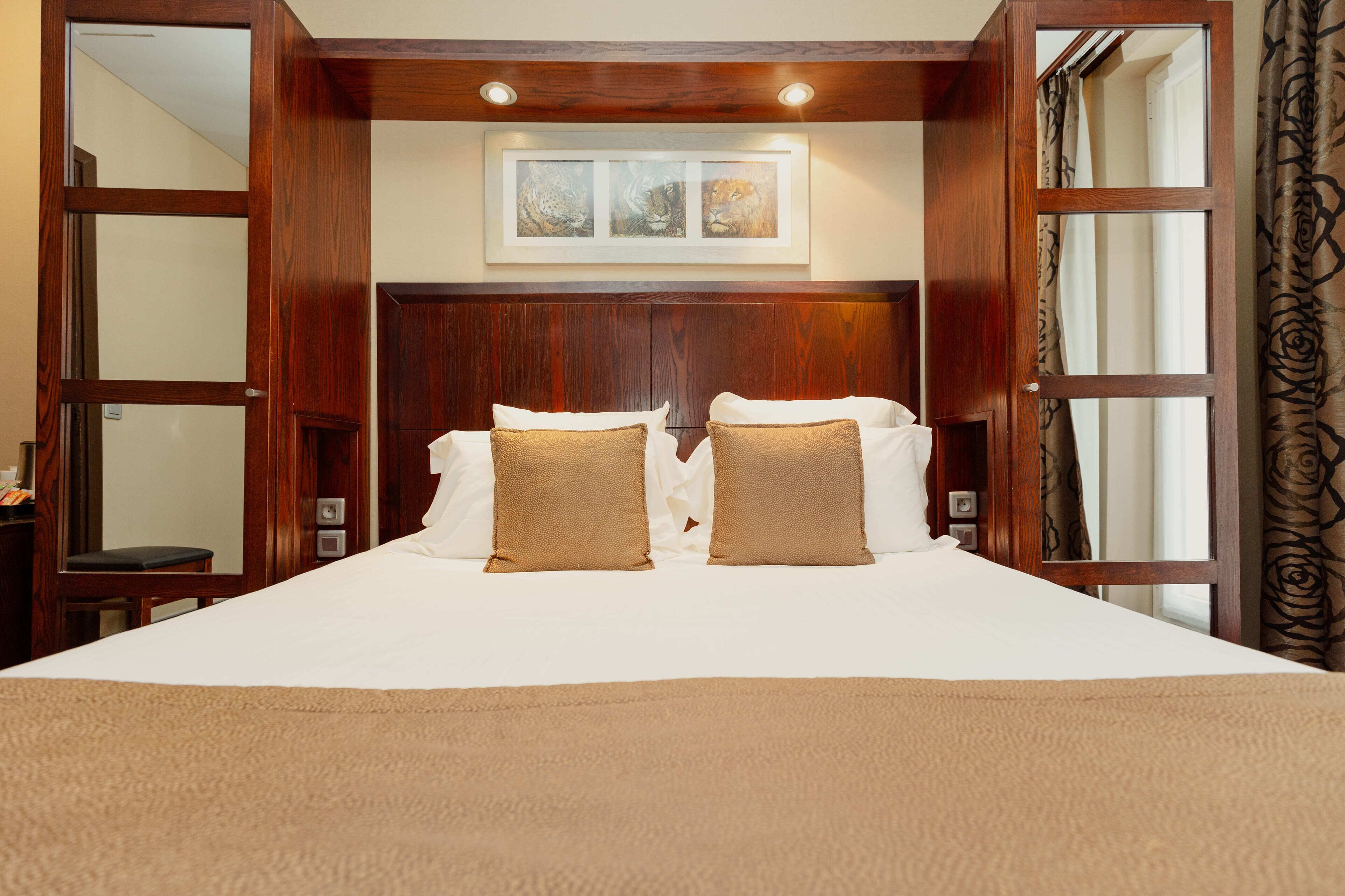 A large bed with a wooden headboard, two pillows, and a beige blanket.