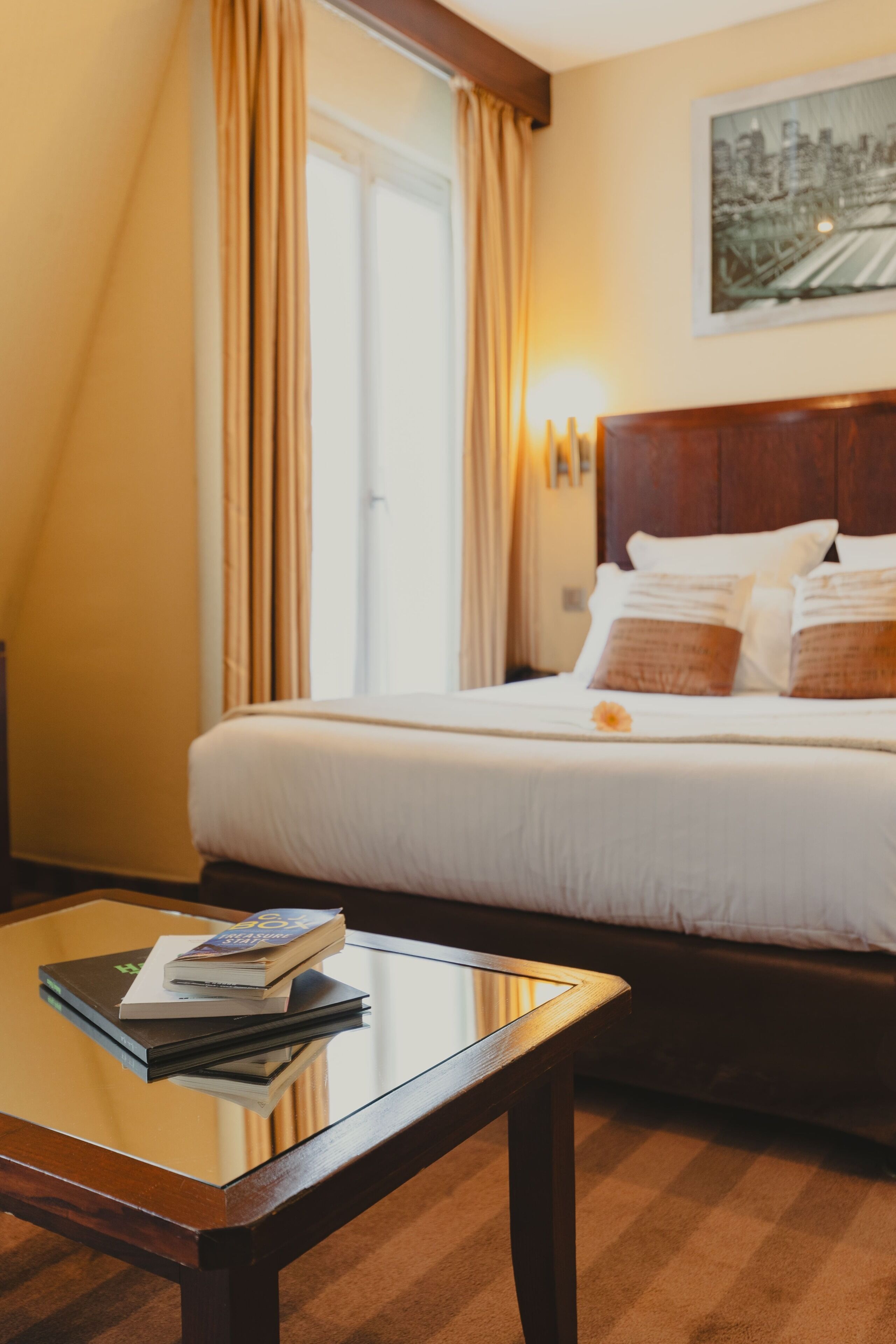 A hotel room with a bed, a nightstand, and a window with curtains.