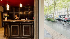 A reception desk with a dark wood finish and pendant lighting. - Grand Hotel Francais (Paris)