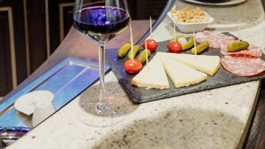 A bar counter with a glass of red wine, a bottle of champagne, cheese, and various snacks. - Grand Hotel Francais (Paris)