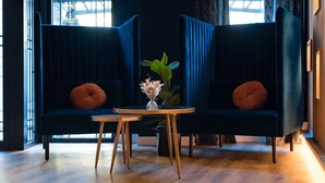 Quarto moderno com dois sofás azul-escuros, uma pequena mesa de madeira e um vaso com flores.