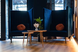 Una habitación moderna con dos sofás azul oscuro, una mesita de madera y un florero con flores.