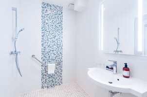 Un baño moderno con ducha, lavamanos y espejo.