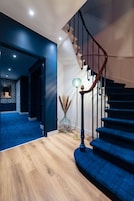 Una escalera moderna con barandillas de madera y peldaños azul oscuro.